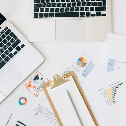 Deux ordinateurs portables sur un bureau avec des graphiques et des documents divers.